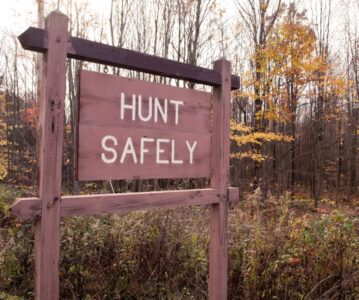 A "HUNT SAFELY" sign in the woods in the fall